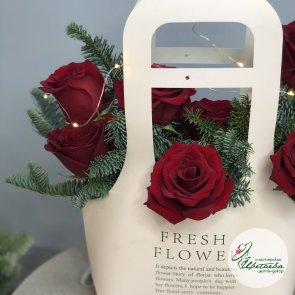 Красные розы с веточками нобилиса в цветочной сумочке