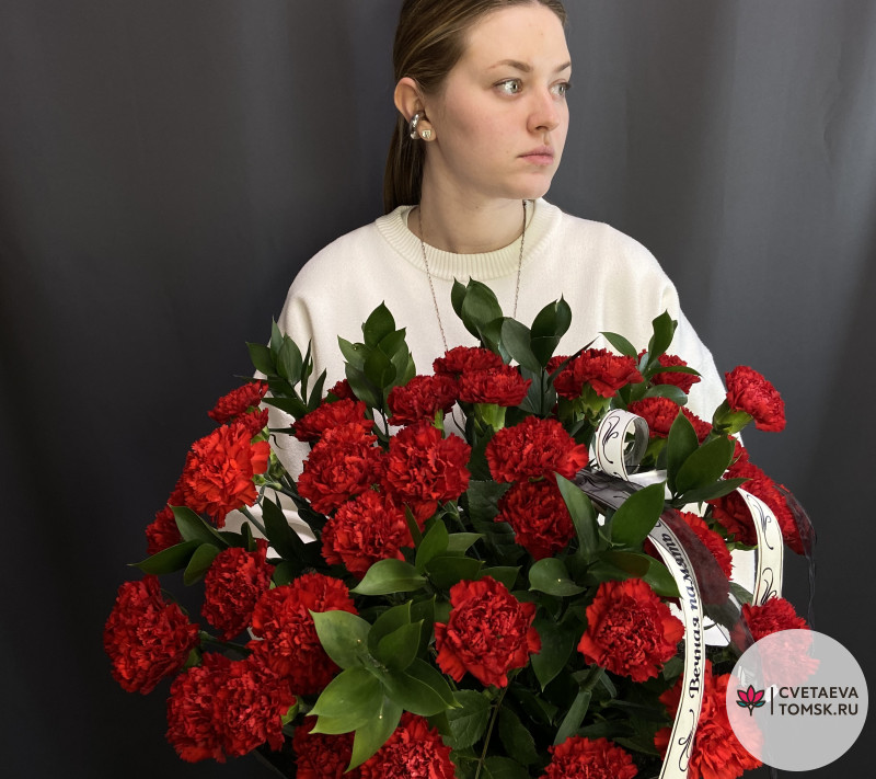 Траурная корзина с красными гвоздиками и зеленью